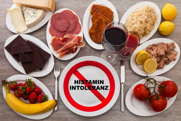 potraviny ako sú banány, kyslá kapusta, spracované mäsové výrobky, červené víno a tvrdé syry sú rozložené na stole s nadpisom histamínová intolerancia