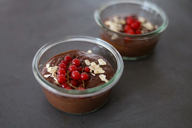 Čokoládový puding je naservírovaný v sklenených miskách, ozdobený je čerstvými ríbezľami a mandľovými lupienkami.
