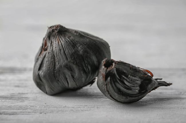 Fermentovaný čierny cesnak účinky. Černy cesnak na drevenom stole.
